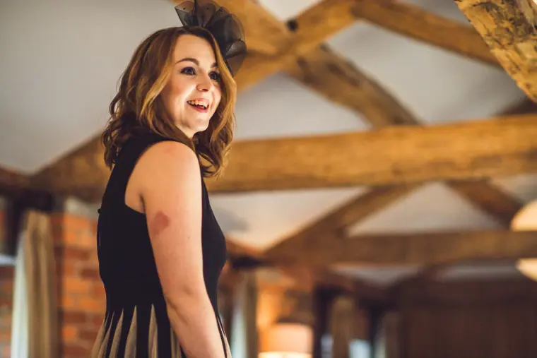 Smiling bridesmaid in a black dress in a timber-beamed room