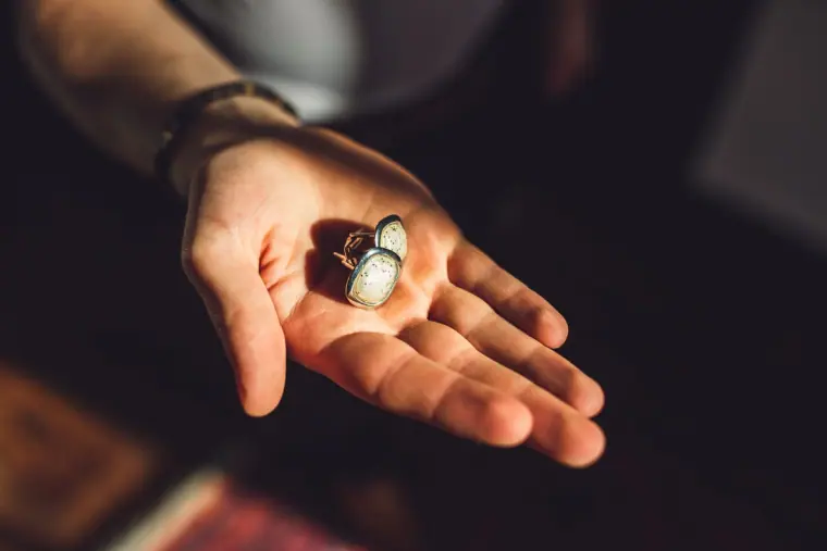Pair of silver cufflinks held in an open palm
