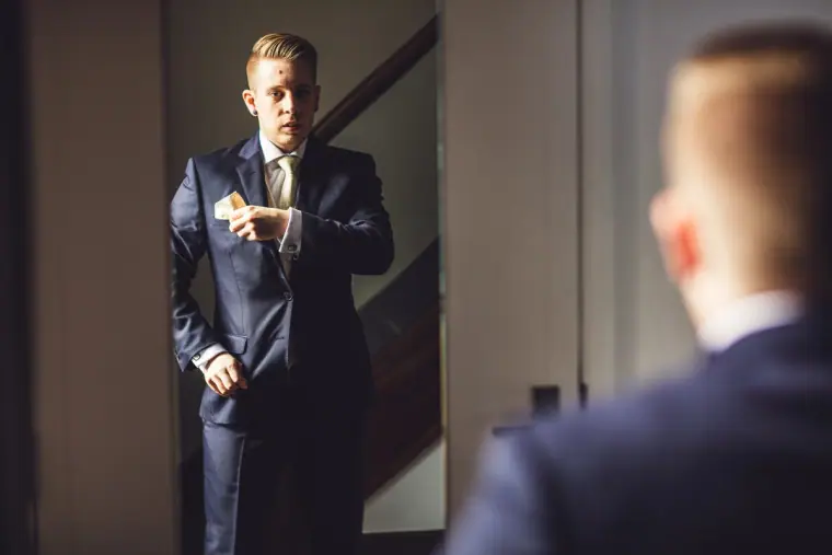 Groom in a navy suit checking his watch in a doorway