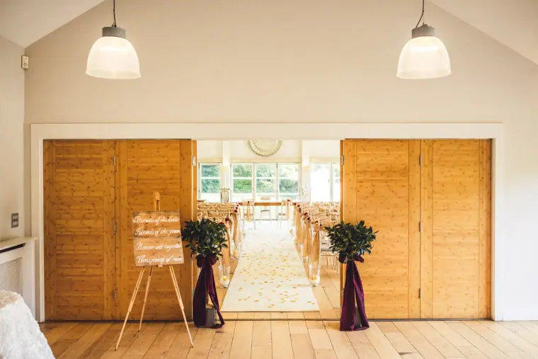 Wooden doors opening onto the ceremony room with a welcome sign on an easel