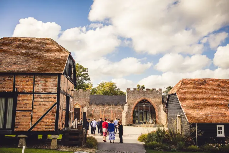 Guests walking towards the arched brick gateway between timber barns, Wasing Park