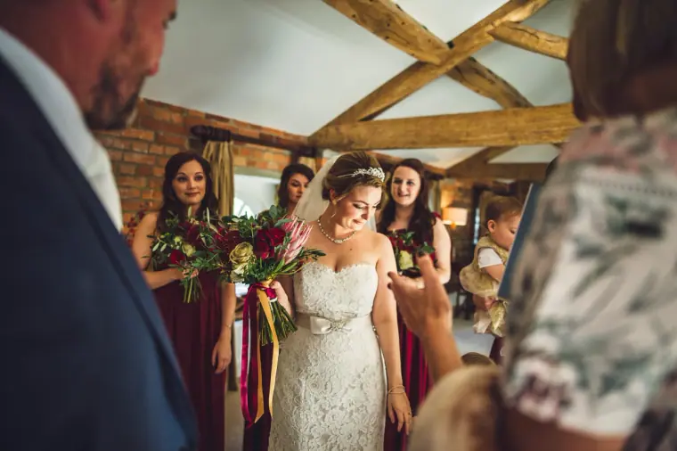 Sarah laughing with bridesmaids holding red and burgundy bouquets