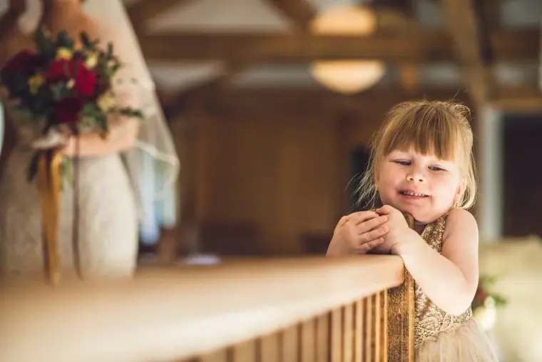 Flower girl smiling over the banister of the landing