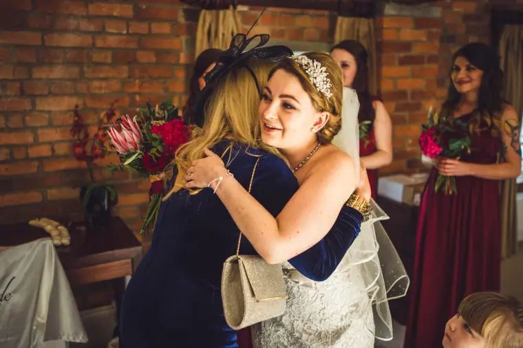 Bride hugging a woman in a navy fascinator in the bridal suite