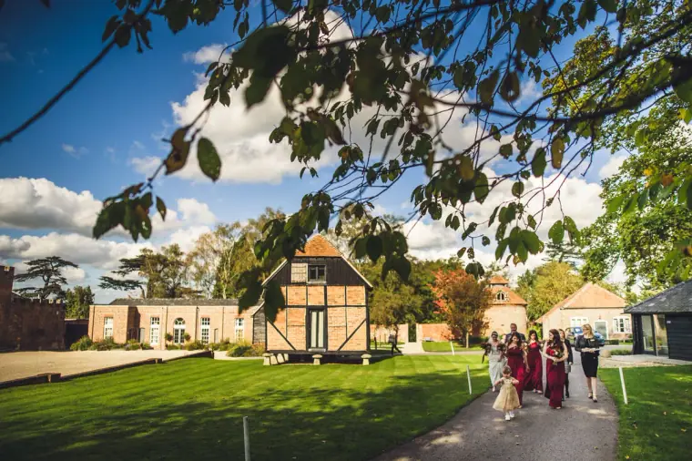 Bridal party walking across the lawn towards the ceremony barn at Wasing Park