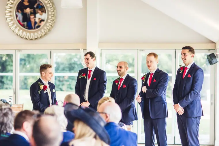 Charlie and his groomsmen in navy suits waiting at the front of the ceremony room