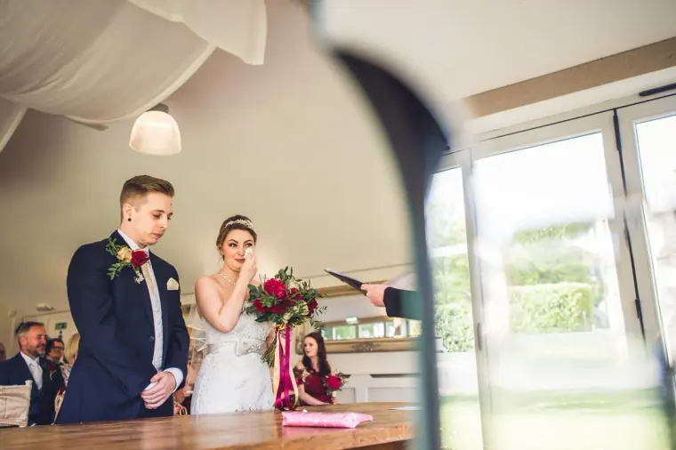 Sarah and Charlie standing before the registrar in the bright ceremony room