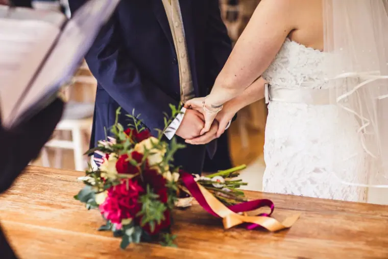 Red and burgundy bouquet with trailing ribbons resting on the registrar's table