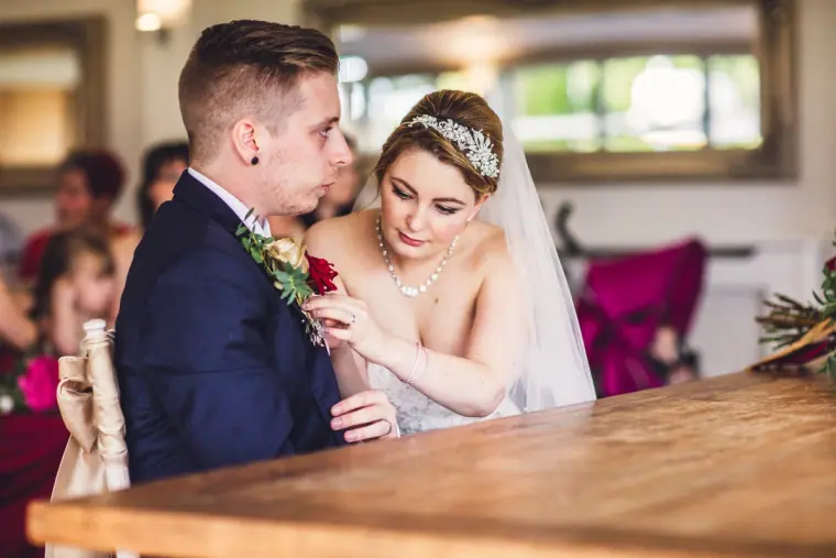 Sarah and Charlie signing the register at a wooden table