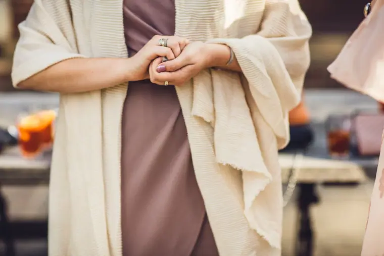 Guest in a cream shawl clasping her hands