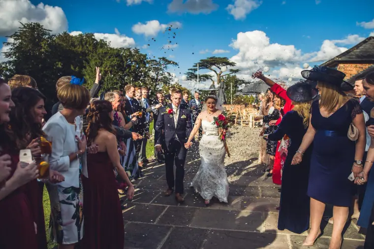 Newlyweds walking between rows of guests throwing confetti at Wasing Park