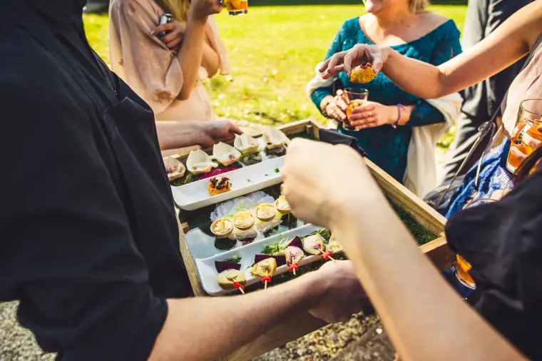 Guests taking canapés from a wooden serving tray during the drinks reception