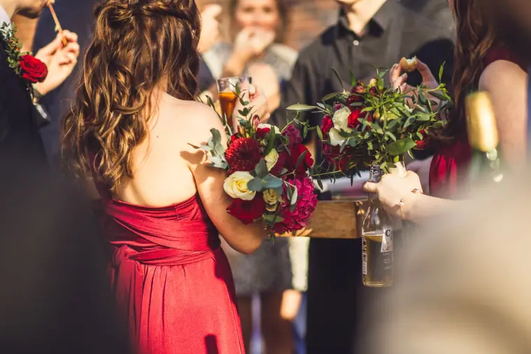 Bridesmaid in red holding bouquets during the drinks reception