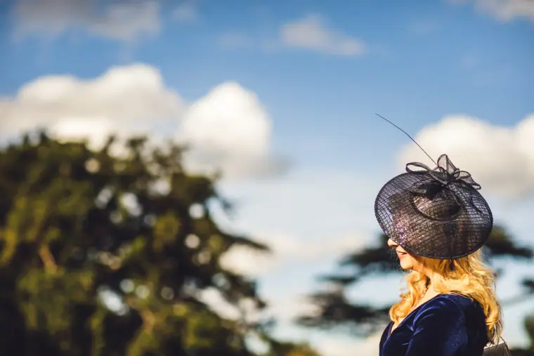 Guest in a black fascinator against a blue sky