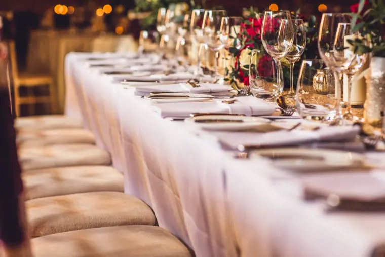 Long top table laid with white linen, glassware and flowers