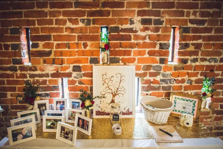 Guest book table with a fingerprint tree and framed photos against brick
