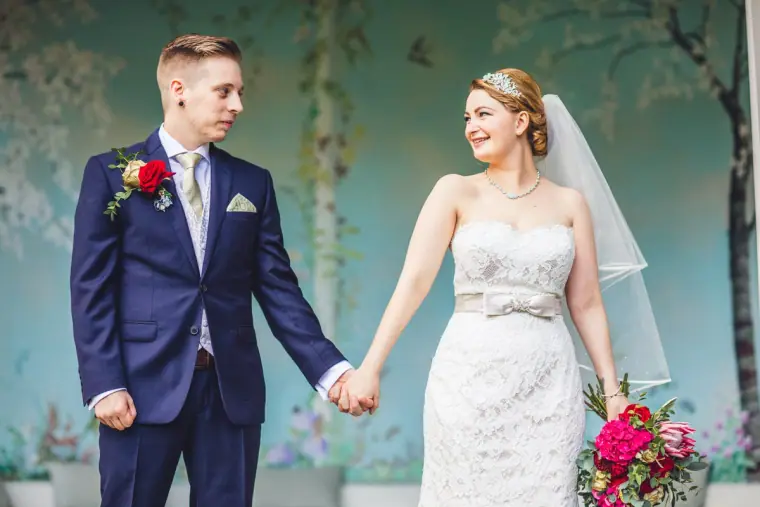 Bride and groom holding hands and smiling in the painted pavilion
