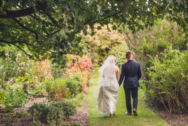 Bride and groom walking away along a path through the flower garden