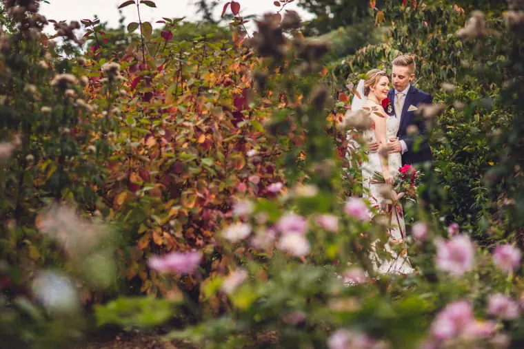 Sarah and Charlie standing among pink flowers in the walled garden