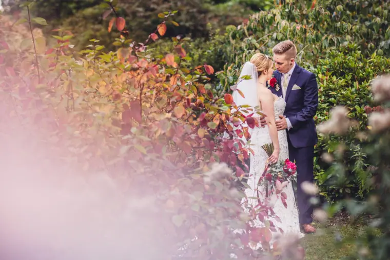 Sarah and Charlie kissing, framed by soft-focus pink flowers