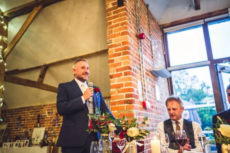 Man in a suit giving a speech with a microphone beside the top table