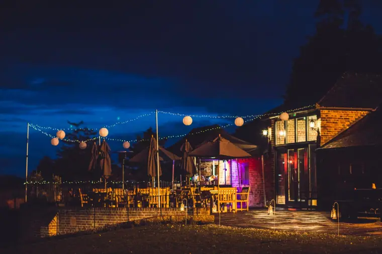Courtyard at night with festoon lights and parasols at Wasing Park