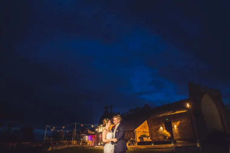 Bride and groom in the dark courtyard under a deep blue night sky
