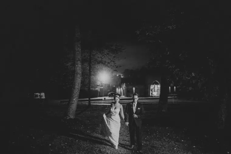 Black-and-white photo of the couple walking along a dark path at night