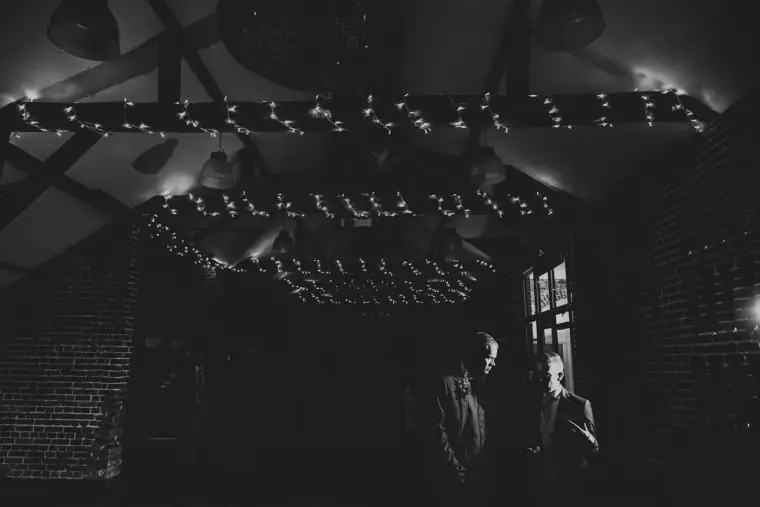 Black-and-white photo of fairy-lit beams over the dark dance floor