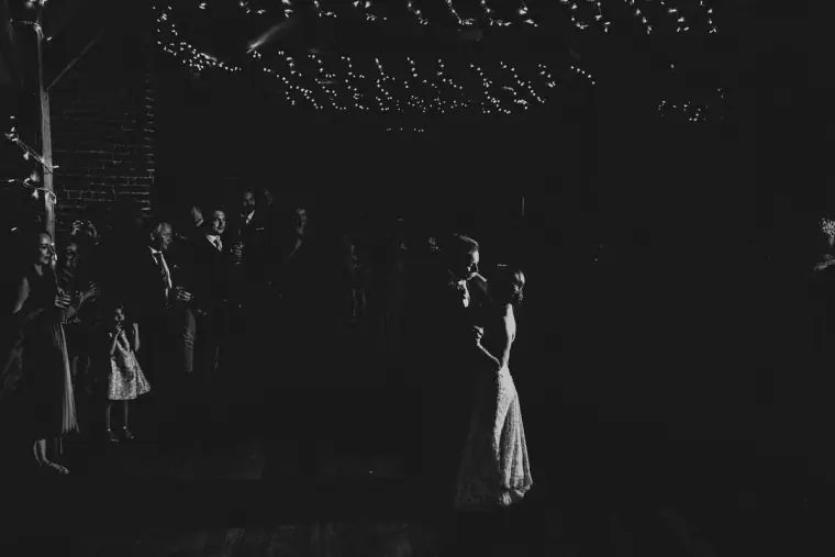 Black-and-white photo of the couple's first dance in a ring of guests