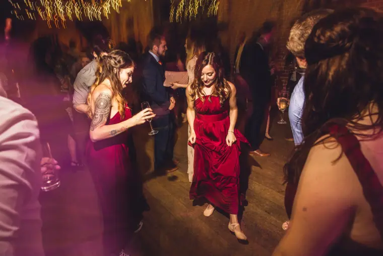 Bridesmaids in red dancing amid motion-blurred lights