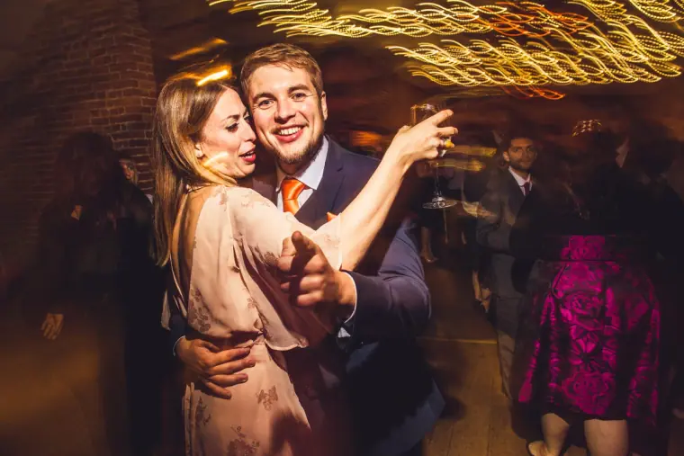 Guest in a pink dress dancing with a man under streaks of light