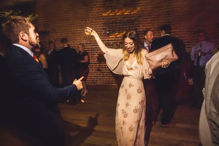 Guest in a sequinned dress dancing with her arm raised
