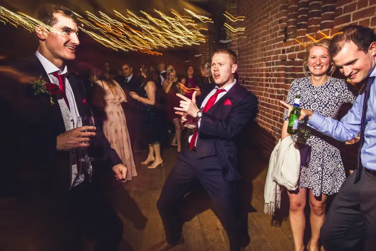 Groomsmen and guests dancing and laughing on the busy dance floor