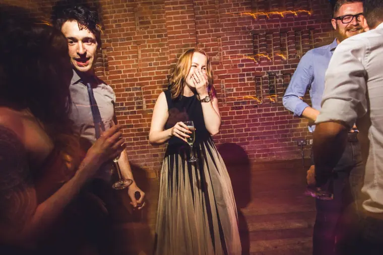 Guest laughing with her hand to her face on the dance floor