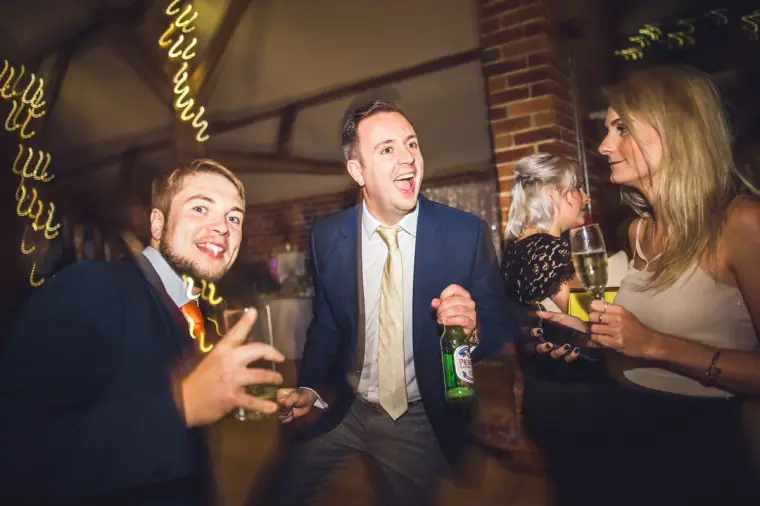 Men laughing with beers and a woman holding a glass of champagne