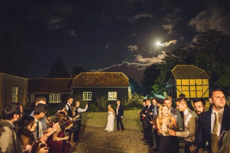 Guests gathering outside under a moonlit sky by the barns at Wasing Park