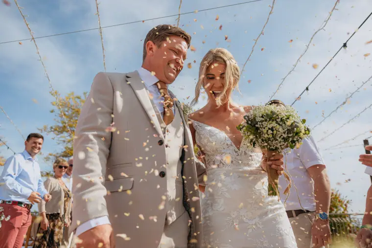 Bride and groom laughing through a shower of confetti at Liopetro, Kouklia