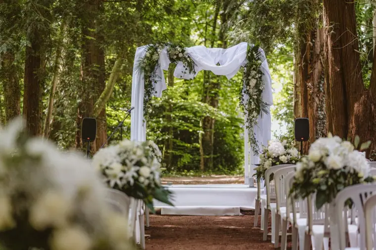 White draped ceremony arch in a woodland clearing at Château de la Basmaignée, France