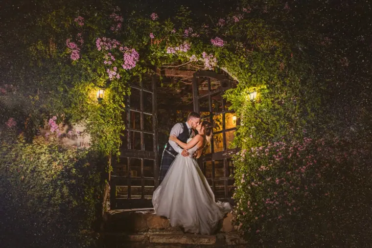 Hannah and Keith kissing at a flower-covered doorway at night, Vasilias Inn, Paphos
