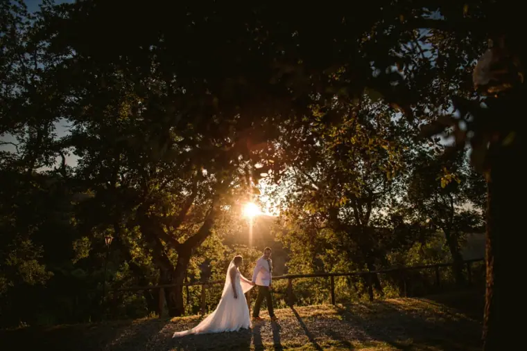 Bride and groom in a woodland clearing with the sun bursting through the trees