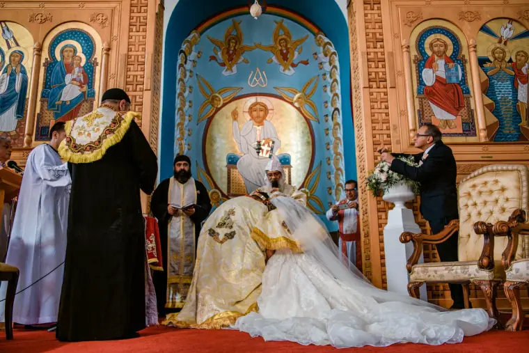 Orthodox priests crowning the bride and groom before a painted icon screen