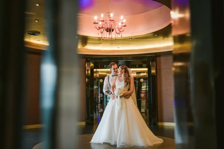 Bride and groom in a hotel lobby beneath a crystal chandelier