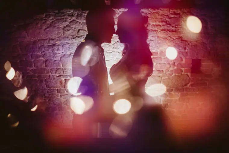 Couple kissing in silhouette through soft coloured lights