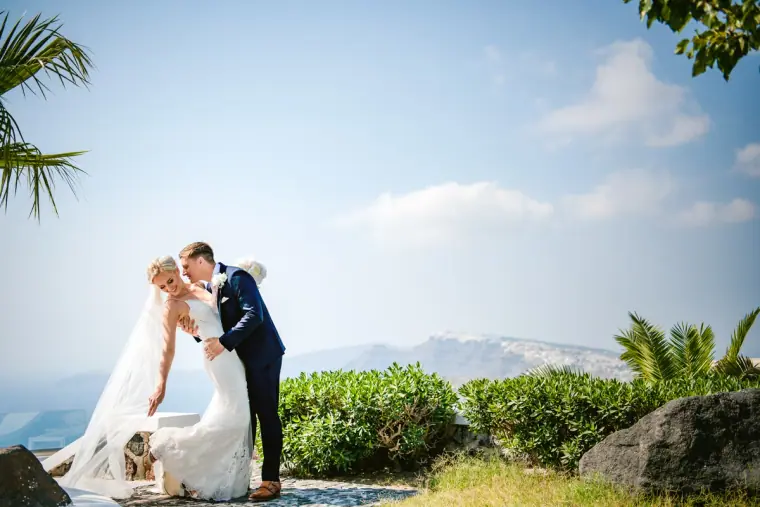 Bride and groom kissing on a cliff top above the sea and distant coast