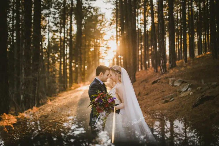 Couple embracing on a pine forest path as low sun streams through the trees