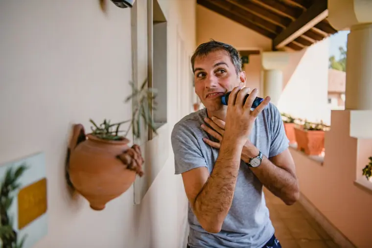 Man pulling a surprised face while holding a small camera on a terrace