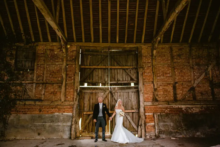 Bride and groom standing in the doorway of an old brick barn