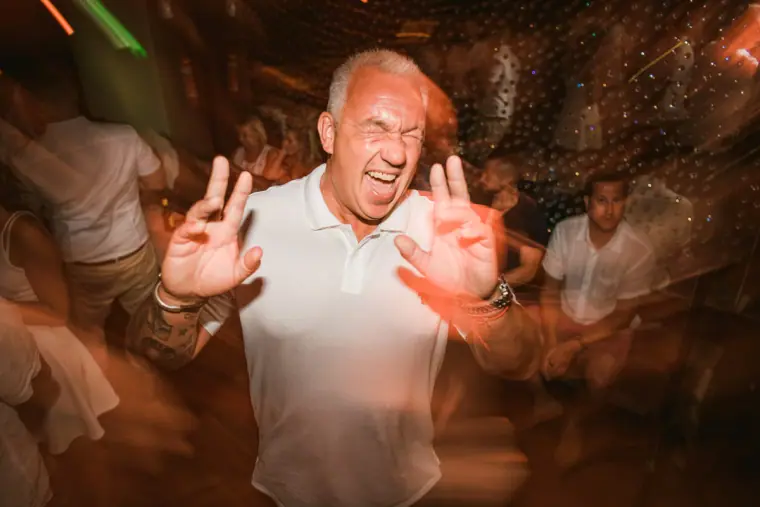 Older guest pulling a playful face while dancing at the party