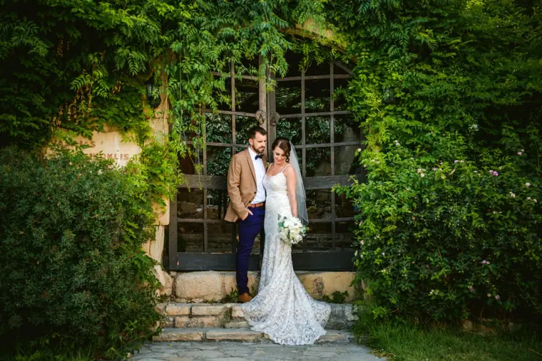 Bride and groom before a vine-covered doorway with stone steps